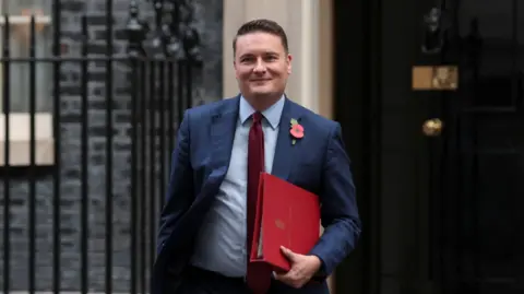 Reuters Wes Streeting outside No 10 Downing Street. He is holding a red folder and is wearing a navy suit