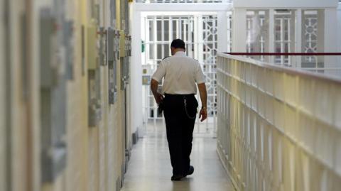 Prison officer walking past closed cell doors