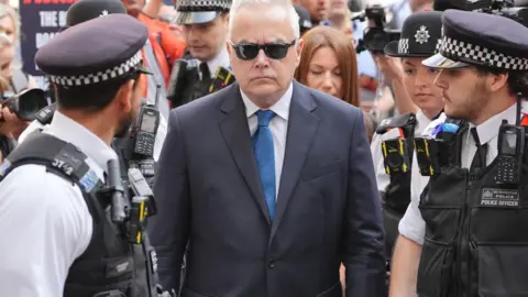 PA Media Huw Edwards flanked by police officers