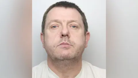 West Yorkshire Police A man with stubble and short dark hair looks at the camera