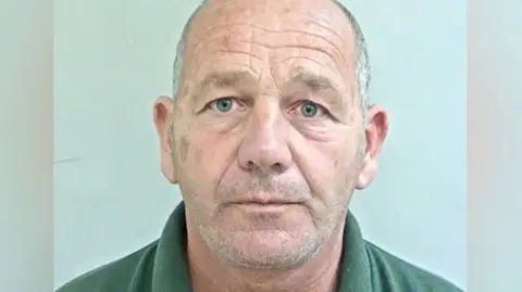Lancashire Police Police custody image of Stephen Worden. He has cropped white hair and stubble and is wearing a green polo shirt