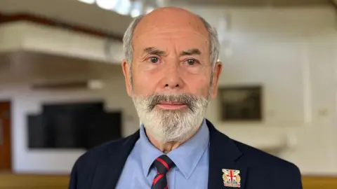 A man with a beard in a jacket and tie