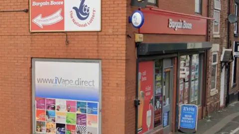 The front and side of a red brick shop, with Bargain Booze written across the top and side