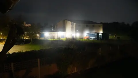 Upton Junior School building, with bright lights shining on the outside at night-time.