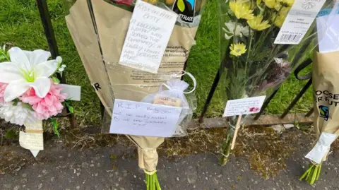 Four bouquets of flowers leaning against a black fence.