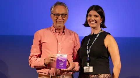 Richard Snow with BBC presenter Katie Tyler in front of a purple background