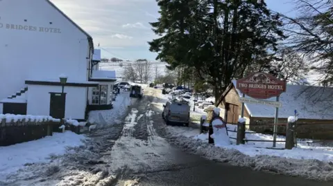 Image showing an icy and frozen road near Princetown, Devon. The image has been taken outside the Two Bridge Hotel, a white building with black windows.