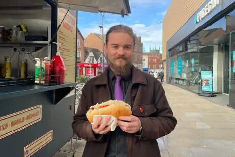 Christopher Bridgwood holding a hotdog