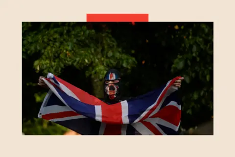 PA An individual waving an Union flag during anti-immigration protest in Belfast city centre