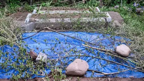 Getty Images The grave of the twins. A blue plastic sheet is spread over their grave.