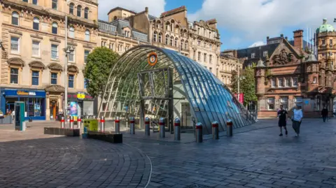 St Enoch Square in Glasgow surrounded by shops and businesses with a glass entrance to St Enoch Square in the centre.