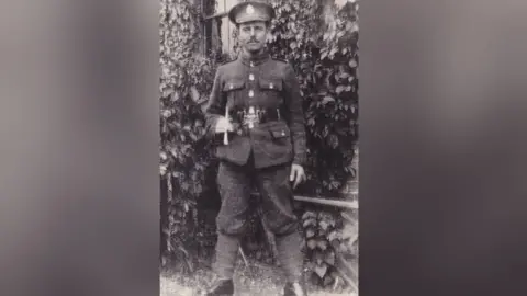 David Stuckey A soldier is seen in an old black and white, grainy photo. He is wearing an Army uniform typical of World War One. He has a moustache