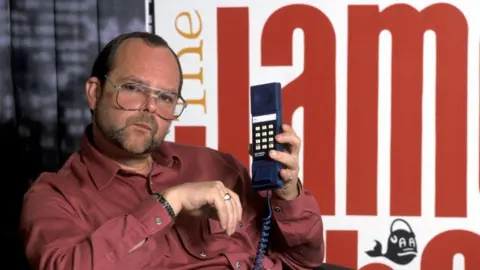 ITV/Shutterstock James Whale is photographed holding up a phone handset in a publicity shot for his Radio Show in the 1980s