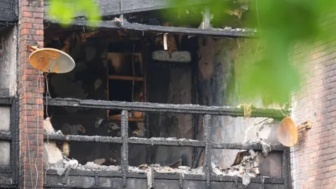 PA Media A close-up of the severely fire-damaged building