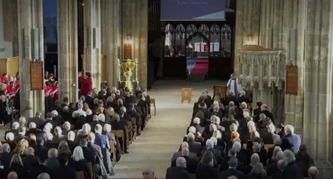 Lines of people sitting in plow minster at the funeral. The photo is seen in front of the minster