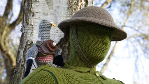 Mandy Wright Photography A grey knitted pigeon sitting on a green knitted soldier 