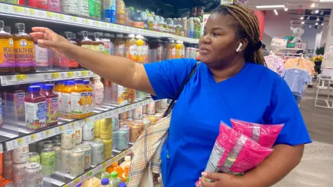 Daniel Qay/BBC Yanic Clark, um estudante de enfermagem em Manhatton que se identificou como lojas de baixa renda na seção de supermercado de uma posição alvo em 1025 de setembro. Ele alcançou dois sacos de produtos para beber uma bebida da Ilha da Mercearia.