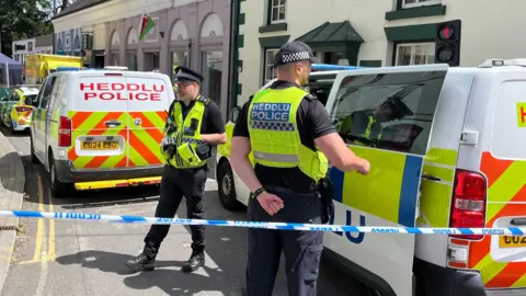 Police officers standing next to a cordoned-off area in Church Street, Welshpool