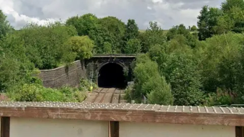 Entrance to Standedge Tunnel, with trees surrounding the rail lines.