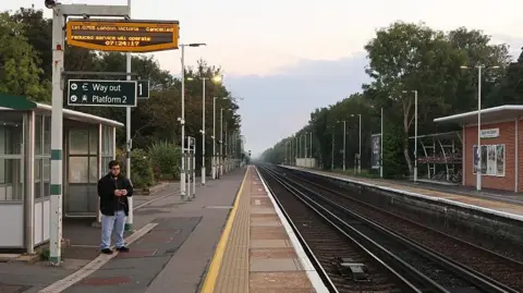 Getty Images A lone passenger waiting at an empty Hassocks station, with a cancelled train sign above