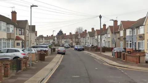 Google A Google StreetView image of First Avenue in Dagenham, with rows of terraced houses on a bending street with cars parked on the pavement