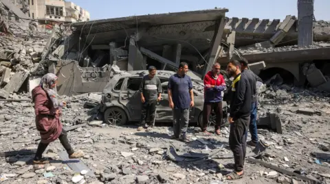 People walk amid the rubble of a building destroyed in an overnight Israeli strike in Jabalia on 18 March.