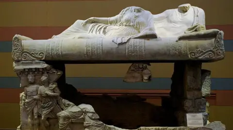 Getty Images An ancient sacrophagues that features large sculptures of seated woman and man, their heads missing 