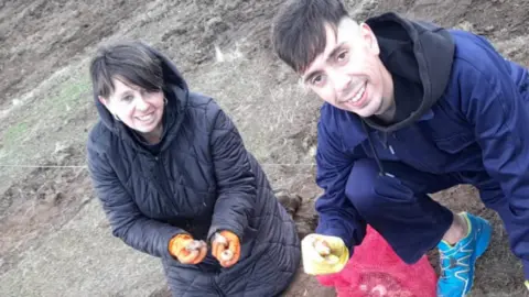 David Mardones Peca and David holding daffodil bulbs wearing gloves and looking at the camera.