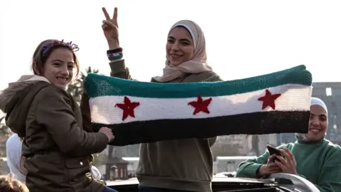 Getty Images Syrians gather at Umayyad Square to celebrate the collapse of 61 years of Baath Party rule with songs and convoys of cars in Damascus, Syria on 9 December 2024