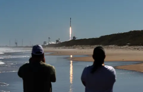 Getty Images Orang-orang menonton dari Cape Canaveral, Florida, saat SpaceX meluncurkan 49 satelit Starlink dengan roket Falcon 9 