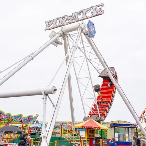 Skegness Pleasure Beach A side view of a pirate ship as it swings into the sky, with people on board, on the fairground attraction 