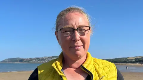 Jo Nuttall has blonde hair, spectacles and a yellow body warmer