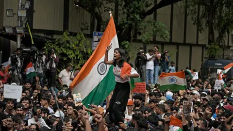 NurPhoto via Getty Images Protesters raise slogans, hold placards and wave Indian flags during a demonstration in Mumbai, India, on July 24, 2026. 