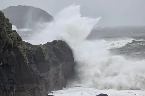 Muddy-Paws / BBC Weather Watchers Large wave crashing against coastal rocks.