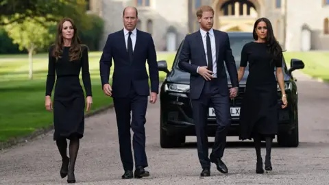 PA Media The Prince and Princess of Wales, pictured with former Duke and Duchess of Sussex, Harry and Meghan. The four of them stand together in a row. Meghan and Harry are hand in hand while Kate and William stand side by side. 