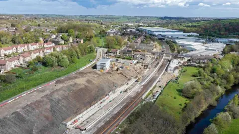 Network Rail An aerial image of work being carried out on a railway line which goes through rural land with houses on one side. 