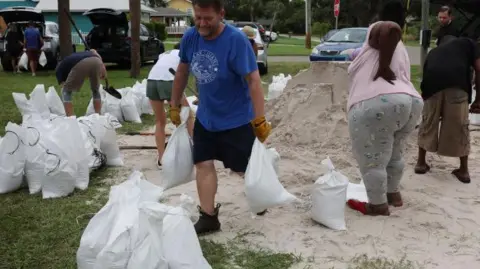 Getty Images Orang-orang mengisi karung pasir saat negara bagian bersiap menghadapi datangnya Badai Milton di St Petersburg, Florida