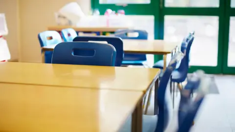A general view picture of plastic chairs and desks in a classroom.