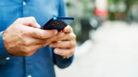 Getty Generic image of a mans hands holding a phone