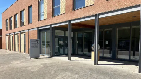 The Rutherford centre, a two story red brick building with a section of glass frontage on one half of the ground floor.