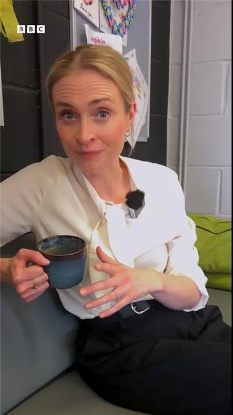 BBC reporter Esme Ashcroft wears a white shirt and holds a mug.