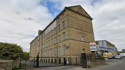 LDRS A beige-coloured multi-storey building fenced off by a black gate. 