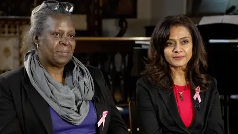 Michele Smith and Harsha Evangeli sit next to each other, wearing pink ribbons in memory of Elianne