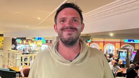 Oliver Conopo/BBC David Stockwell in a beige hooded top at Barratts