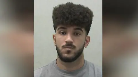 Northumbria Police A mugshot of Azarbonyad who is looking into the camera with pursed lips. He has dark, curly hair and a black beard and moustache. He is wearing a grey top.
