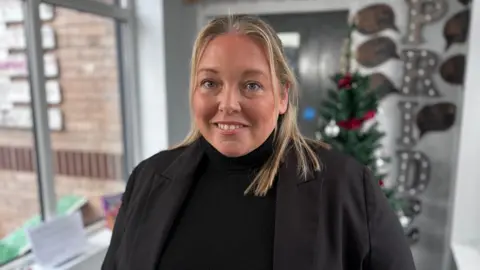Portrait shot of school head Colette Morris, standing in a school corridor