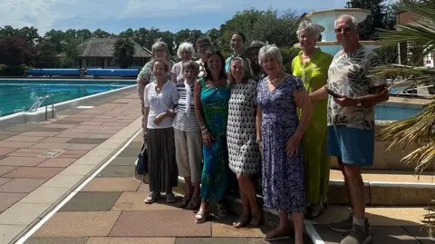 Contributed A group of 12 people standing next to the pool at Hitchin Lido. They are all looking directly at the camera.