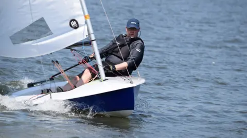 Man steering a sailing boat on a lake