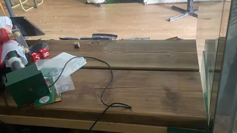 Erin Zdrava The wooden counter of a cafe, showing the power lead that was once connected to the till.