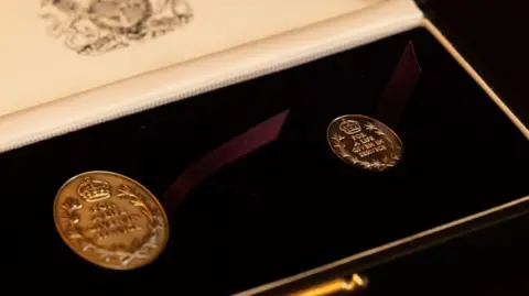 PA Media A presentation box holding two circular gold medals bearing the words "For a life given in service".